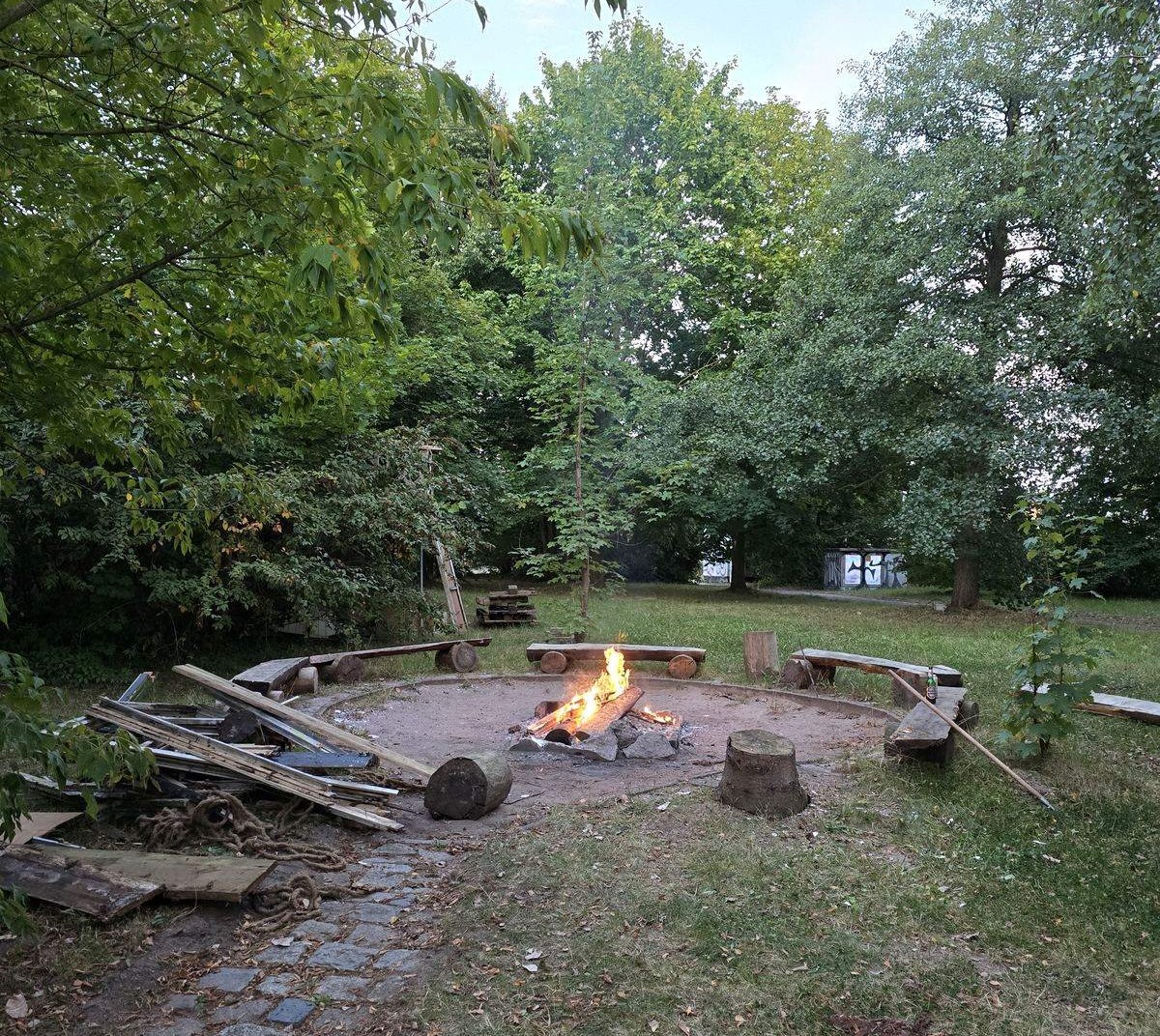 Feuerstelle mit Sitzkreis aus Baumstämmen im Garten des AJZ